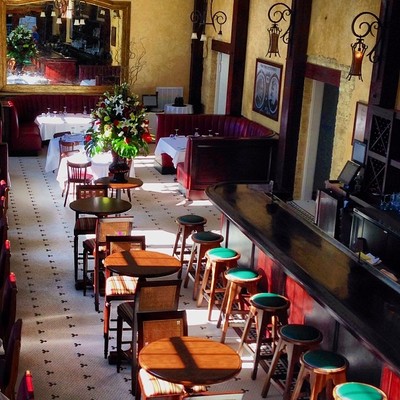 Restaurant interior with bar stools and wooden tables.