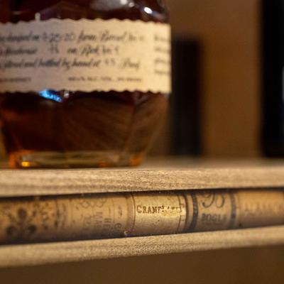 Bottle of Single Barrel Bourbon whiskey on a wooden shelf.