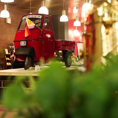 Red Piaggio Ape displayed inside of the restaurant.