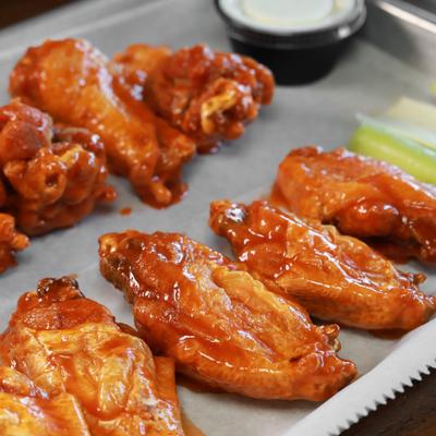 A tray of buffalo wings with celery sticks and ranch on the side.