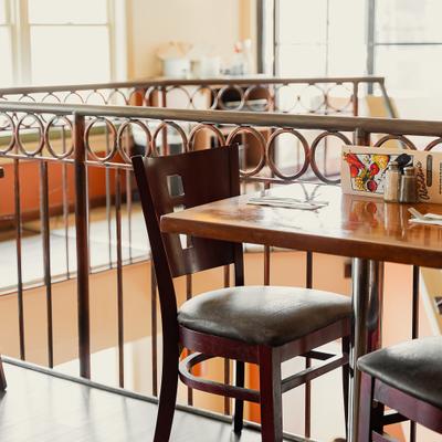 Wooden table with a black leather chair beside a metal balcony railing.