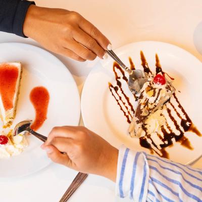 Two hands scooping small pieces of cake off plates.