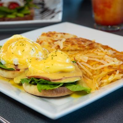 Eggs Florentine with hollandaise sauce served alongside hash browns.
