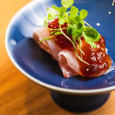 Tuna slices topped with a sauce and micro greens.