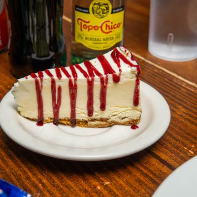 New york cheesecake slice topped with red sauce drizzle.