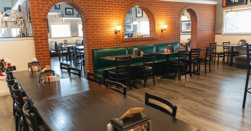 Interior with brick partition, wooden tables and green booth seating