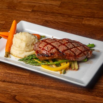 Grilled steak served alongside sauteed veggies and mashed potatoes.