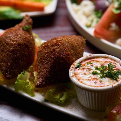 Kibbeh appetizer served with a dipping sauce.