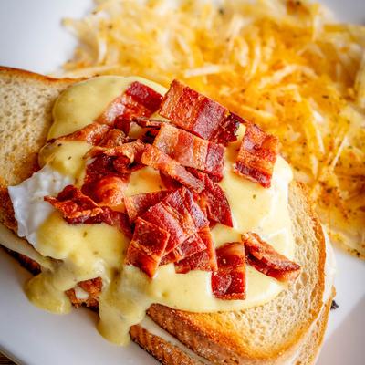 Grilled Cheese on Sourdough topped with two poached eggs and hollandaise sauce..