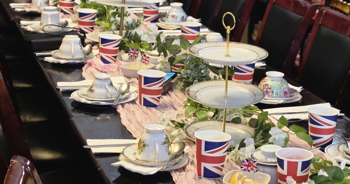 British-themed afternoon tea setup with Union Jack paper cups, and tiered cake stands