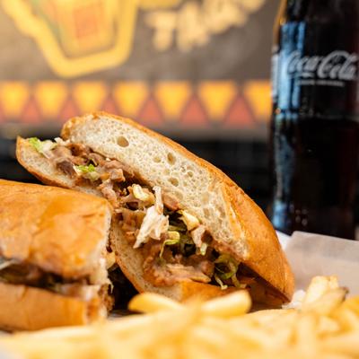 Mexican torta sandwich served with fries and a bottle of sodac.