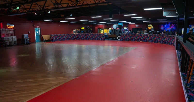 Interior of a brightly lit roller-skating rink with a polished wooden floor