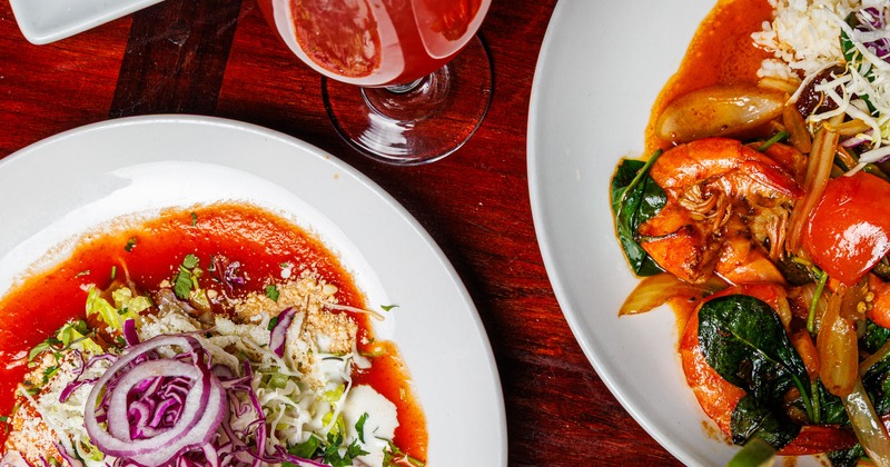Overhead view of two different dishes and a cocktail