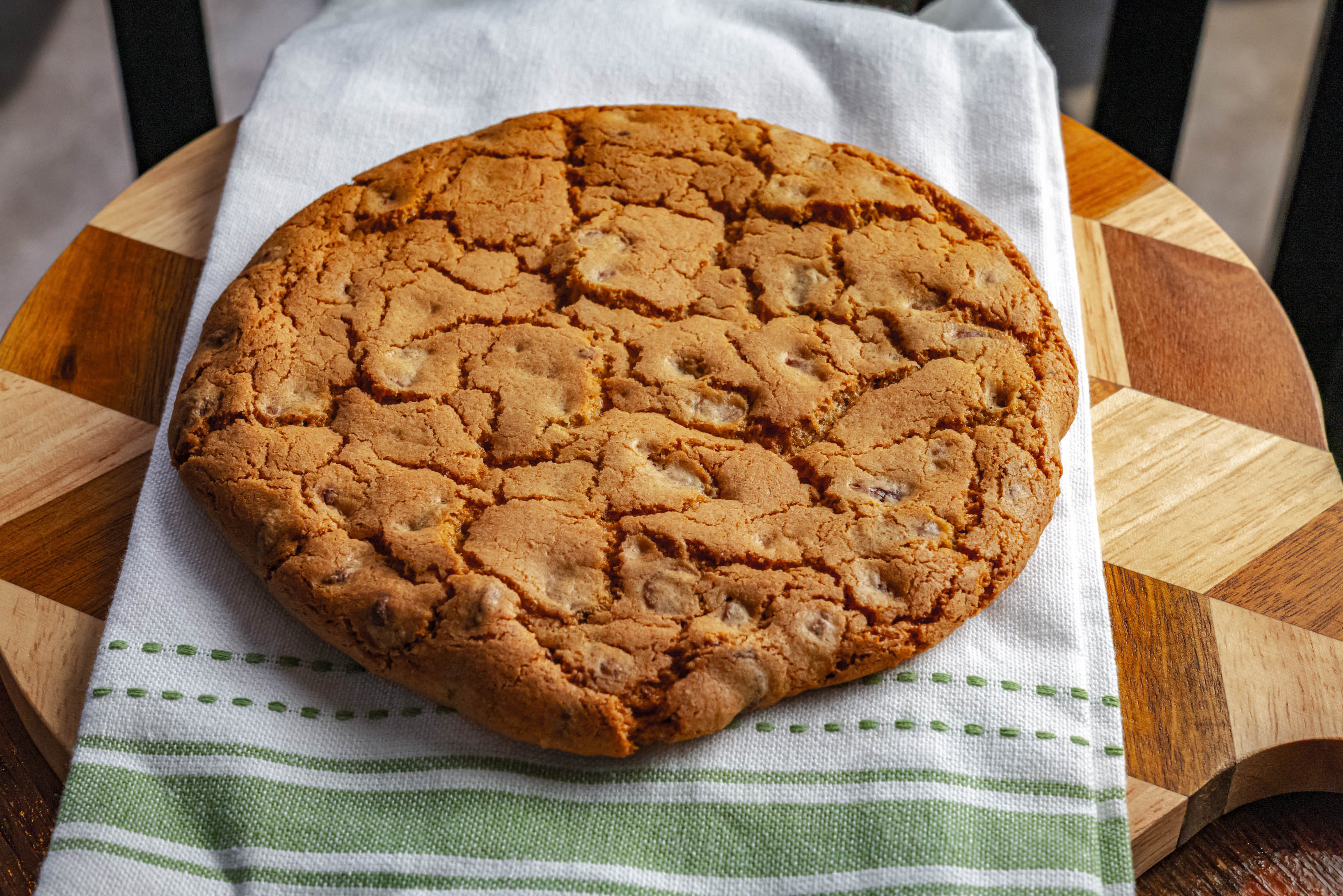 Large chocolate chip cookie resting on a striped cloth