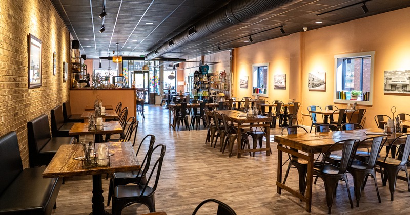 Cozy interior dining area with wooden tables, metal chairs and upholstered bench seating