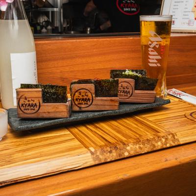 Hand roll sushi set served in wooden stands, alongside alcoholic beverages.