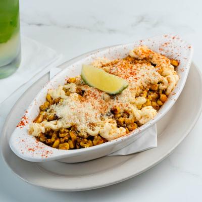 Bowl of Mexican street corn topped with melted cheese, chili powder, and lime.