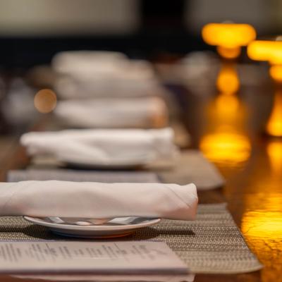 Folded white napkins on plates along a warmly lit bar.
