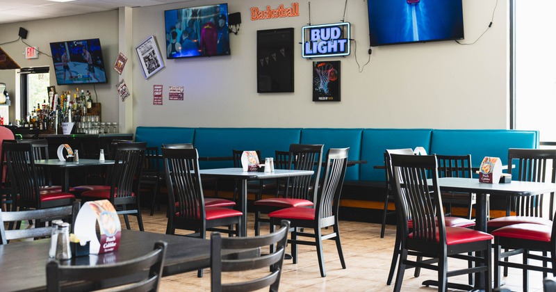 Interior with tables, chairs, televisions and a bar area.