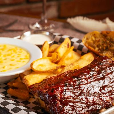 Smoked rib dinner  with sides of potato wedges and creamed corn.