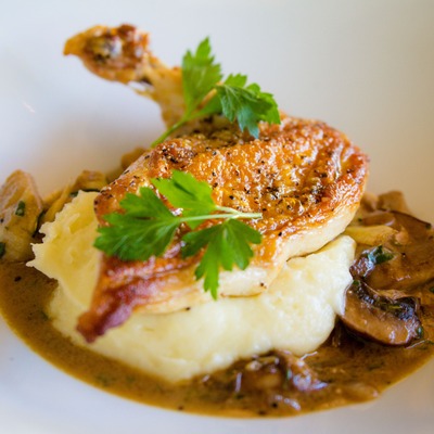 Poultry leg served atop mashed potato and mushrooms.