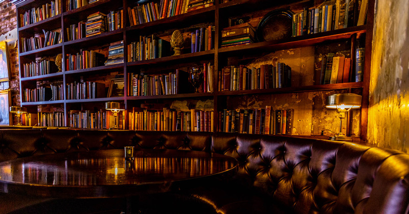 Interior, round leather sofa with a large round table and a wall shelf with books