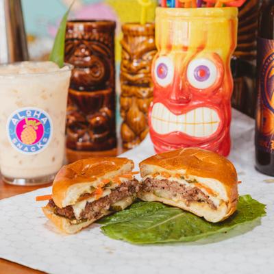 Banh Mi Burger on a table with tiki drinks.