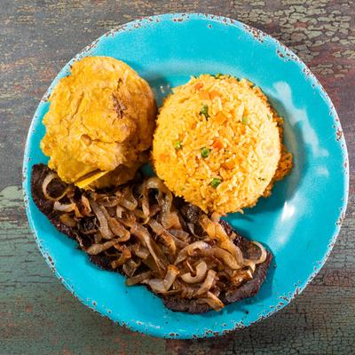 Cuban steak and onions with rice and crispy plantains on a blue plate.
