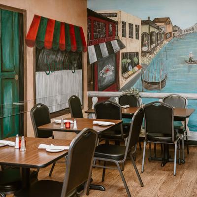 Restaurant dining area with a mural of a canal and colorful awnings.