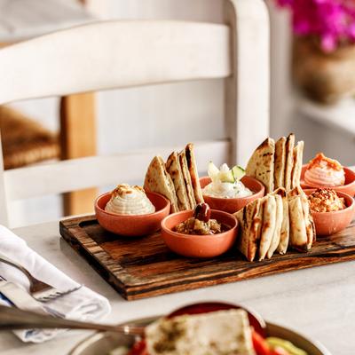 Greek Spreads served on a wooden board with pita bread.