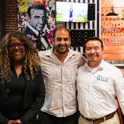 Three people posing for together in a restaurant setting.