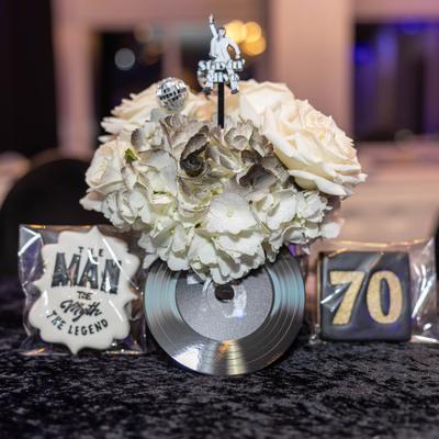 White floral centerpiece with silver record themed decorations.