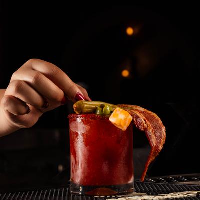 Bartender garnishing a Bloody Mary cocktail.