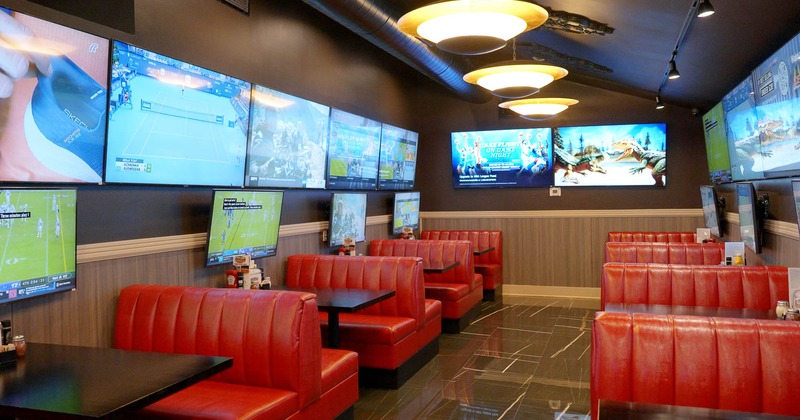 Interior, restaurant booths in room with Tv screens