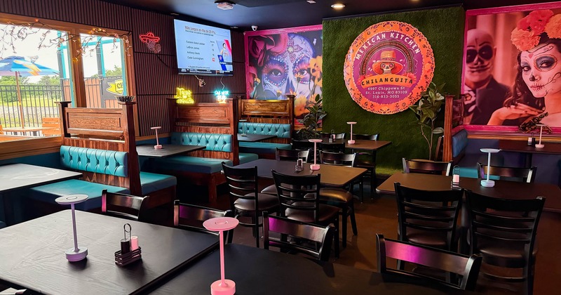 A Mexican-themed restaurant - teal booths, black chairs, a "Day of the Dead" mural
