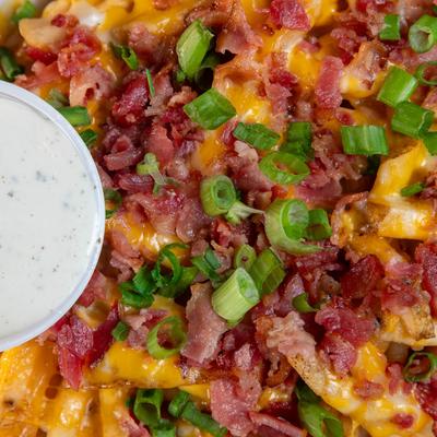 Loaded fries with bacon, scallions, and cheese, close-up.