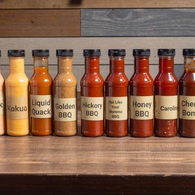 Assorted sauce bottles lined up on a table inside.