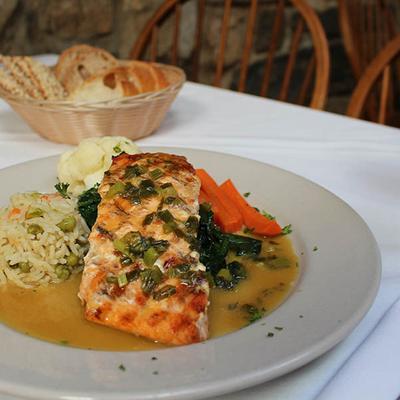 Grilled salmon with orange-ginger-scallion sauce, served with sauteed vegetables and rice.