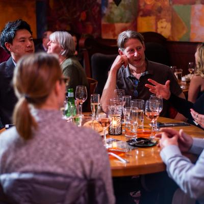 Interior, a group of guests talking at a table with served wines