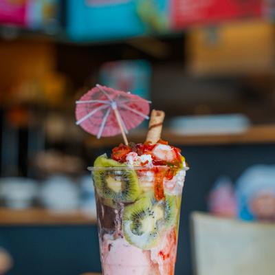 Fruit sunday ice cream cup topped with a drizzle of syrup and a wafer stick.