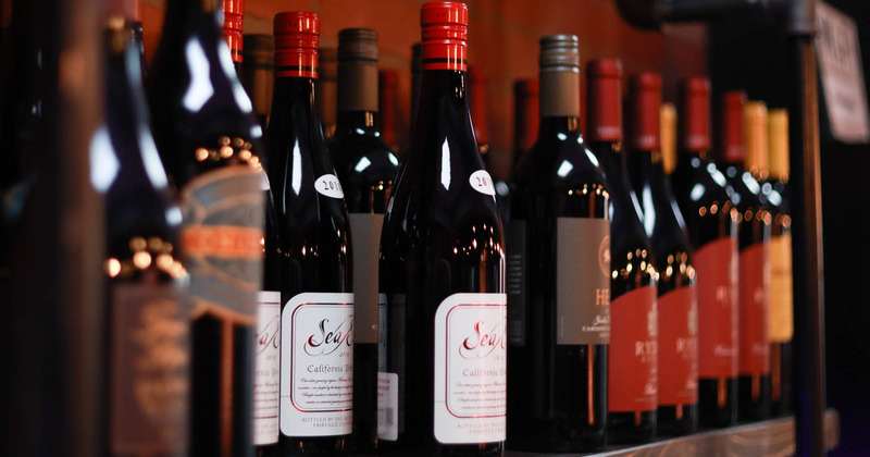 Red wine bottles on a shelf, closeup