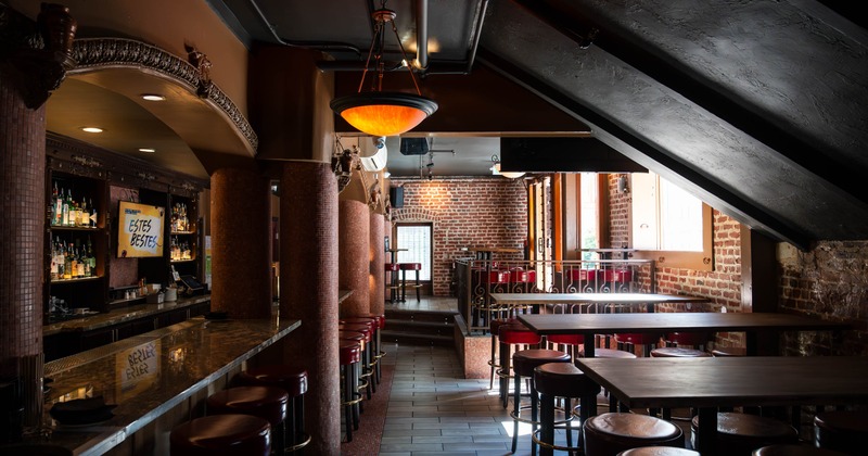 Interior, bar with a marble counter, red bar stools, brick walls, and pendant lighting