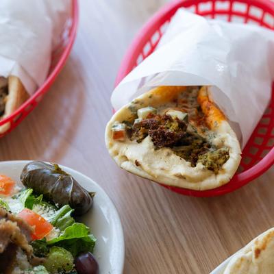 Falafel wrap in a red basket served with a side salad.
