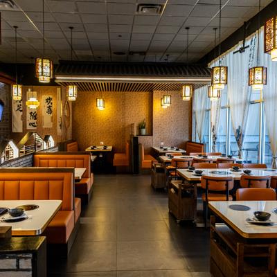 Interior featuring wooden booths, tables set with hot pots and pendant lighting.