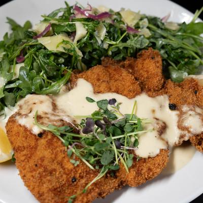 Chicken Milanese topped with arugula salad and lemon butter sauce.