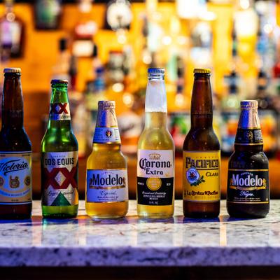 A lineup of six popular Mexican beer bottles on a counter.