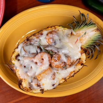 Fajita Hawaiians with steak, shrimp, and melted cheese, served in a pineapple shell.
