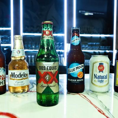 Assorted beer bottles and a beer can on a counter.