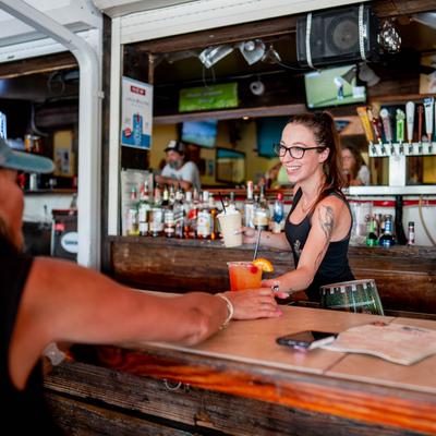 Bartender serving a cocktail to a customer.