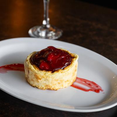 Cheesecake with rhubarb strawberry topping served on a white plate.